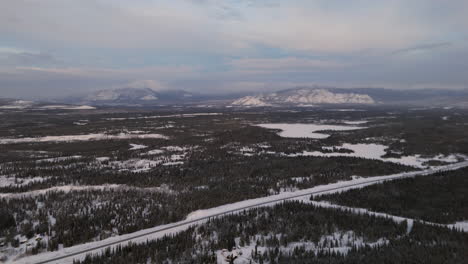 Expansive aerial view of the snow-covered mountains and forested wilderness in Ibex Valley, Yukon, Canada. Captured in the heart of winter, this serene scene showcases nature's untouched beauty.