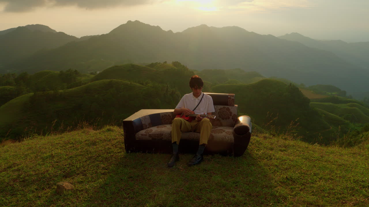 Man Playing Ukulele on Mountaintop at Sunset