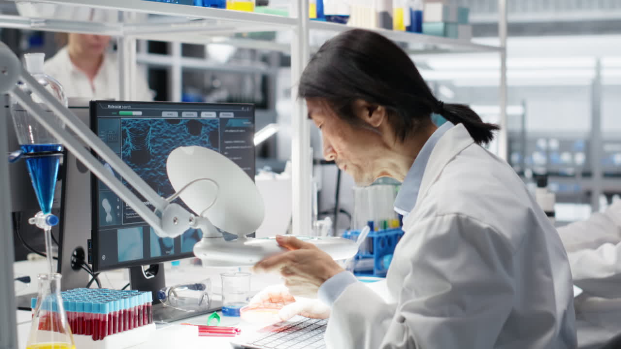 Vertical video Scientist uses laboratory lamp to examine test subject in petri dish