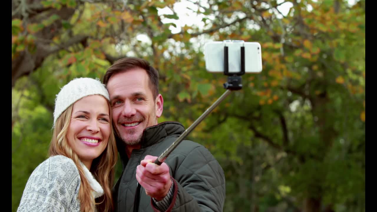 pareja tomando una selfie en el día de otoño en el parque
