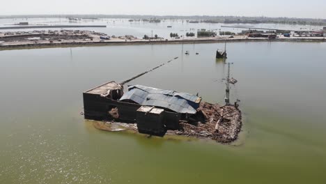 drone takes an anticlockwise rotating shot of the isolated broken house and its surrounding field which submerged by water because of flood in pakistan