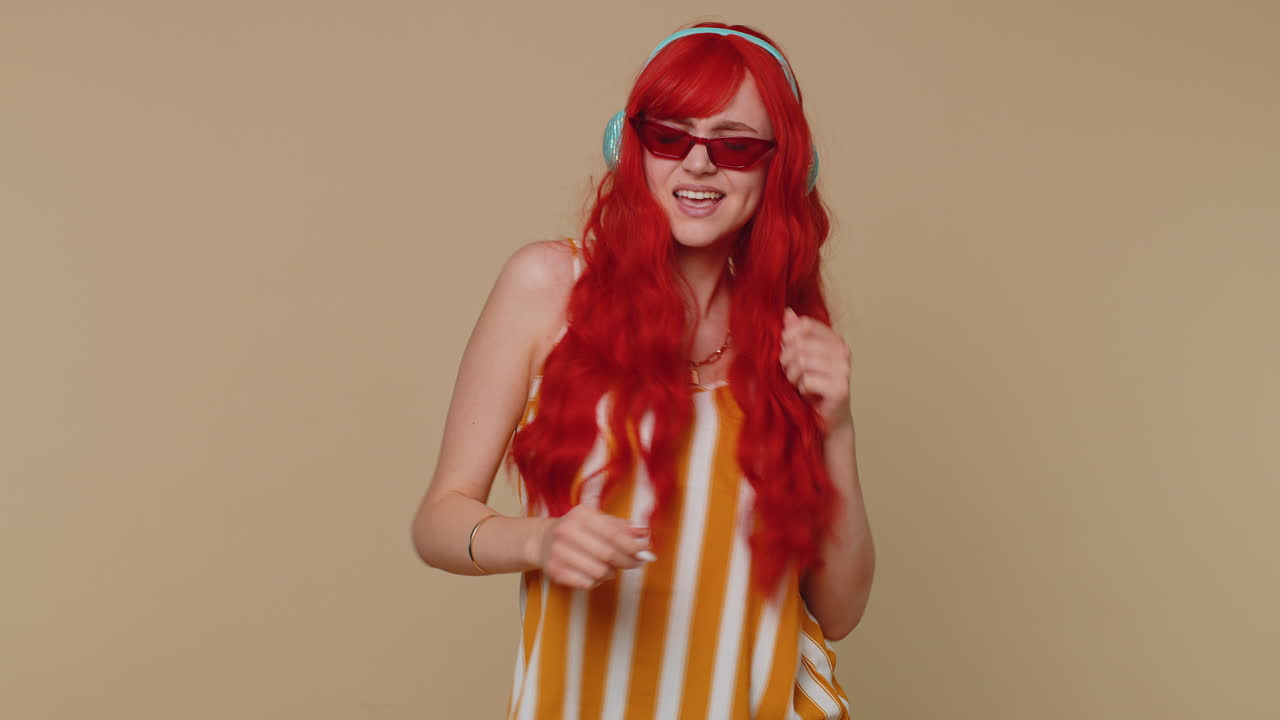 쾌활한 은 머리 여성이 헤드폰을 통해 음악을 듣고 댄스 디스코를 즐기며 놀고 있습니다.