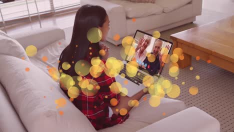 animation of glowing light spots over happy caucasian woman on laptop video call with her family