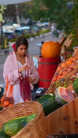 woman shopping for fresh fruits and vegetables at an outdoor market