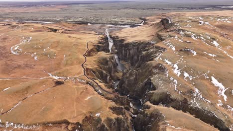 Spectacular aerial of Fjaðrárgljúfur canyon in Iceland, dramatic cliffs, winding river and rugged terrain.