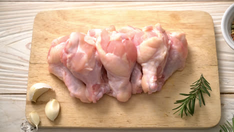 fresh raw chicken wings on wooden board with ingredients