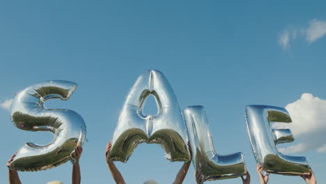 varias personas sostienen globos en forma de letras que componen la palabra venta video 4k