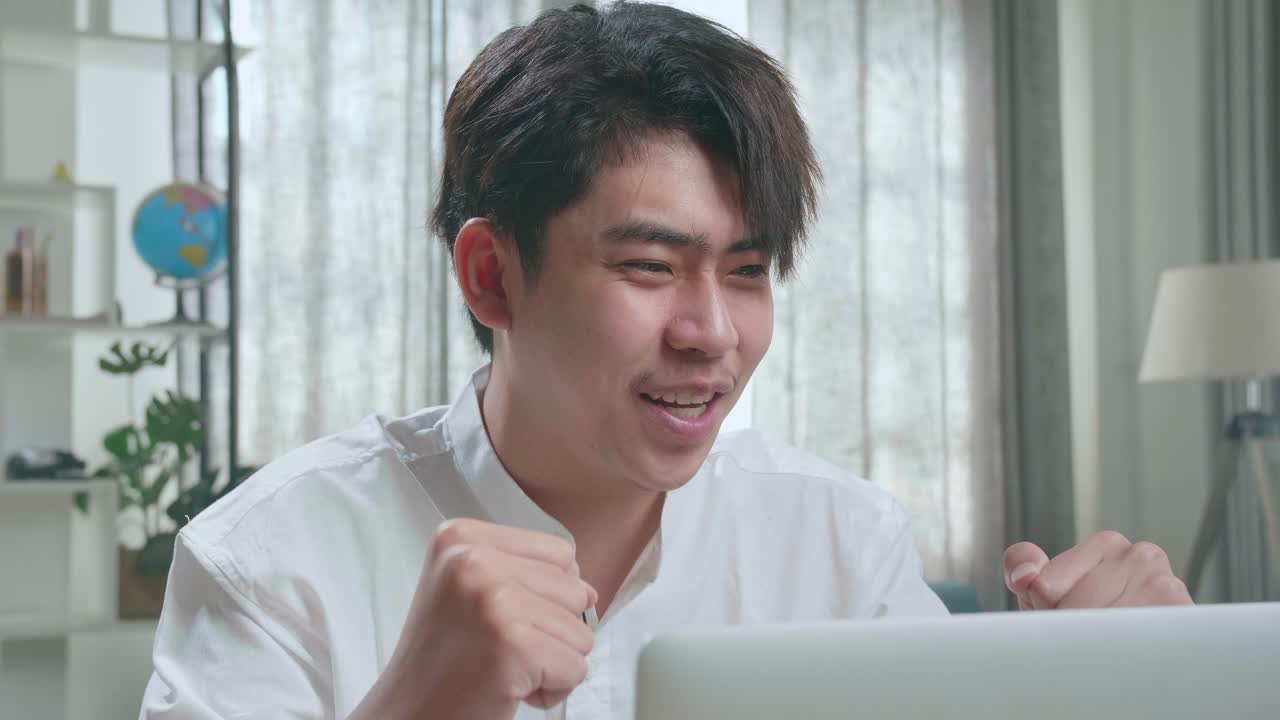 Close Up Of Asian Man Student Celebrating While Using Computer To Study Online At Home
