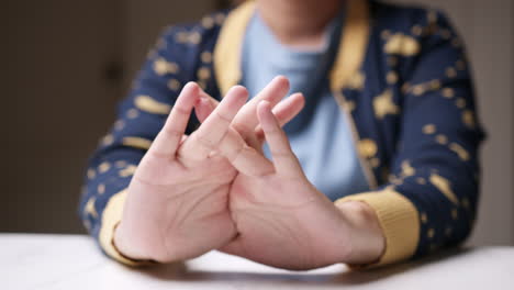 clasping her hands together, a woman is stretching them and squeezing her hands while giving herself a massage to relieve herslef of pain