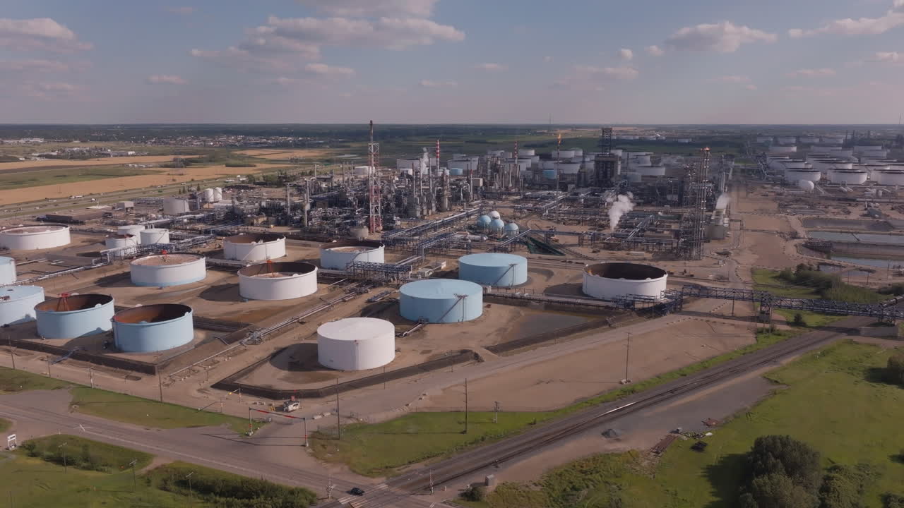 Large industrial plant with storage tanks under clear blue sky
