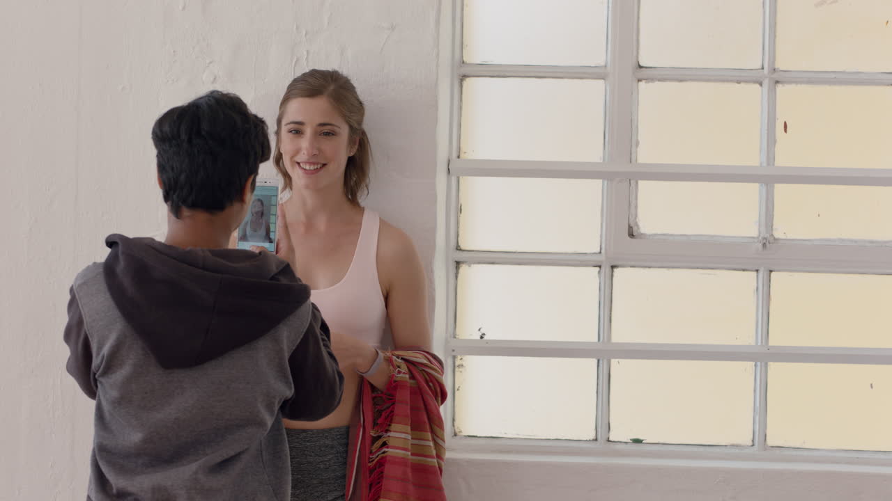 스마트폰을 사용하는 젊은 여성이 운동 후 포즈를 취하는 친구의 사진을 찍고 소셜 미디어에서 연습을 공유합니다.