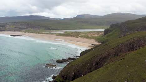 cinematic drone shot passing by a rocky cliff at sanwood bay beach and the north atlantic coast in sutherland, scotland