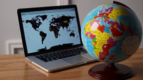 laptop with a globe on a wooden desk