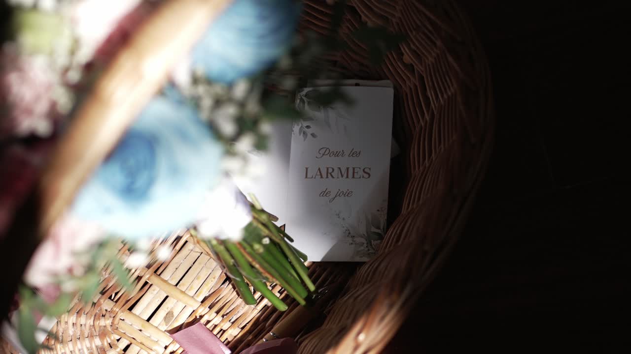card reading 'pour les larmes de joie' lies in a wicker basket with flowers and tissues