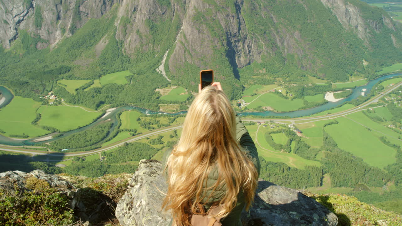 Woman taking a photo of a stunning mountain valley view
