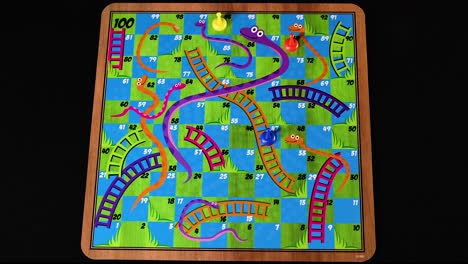 hand moving pieces on snakes and ladders board