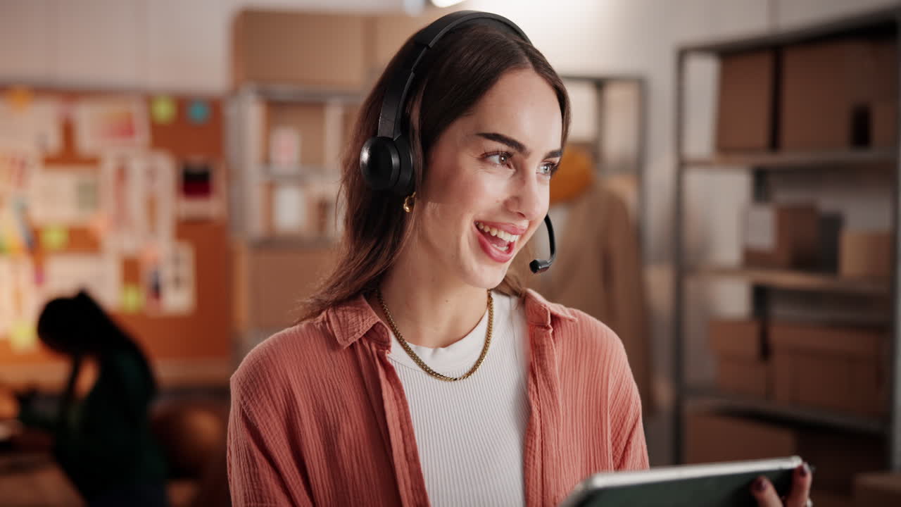 Joven mujer feliz con auriculares usando una tablet en la oficina.