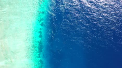 deep blue sea bordered by shallow turquoise lagoon and white sandy beach seen from above in maldives, copy space