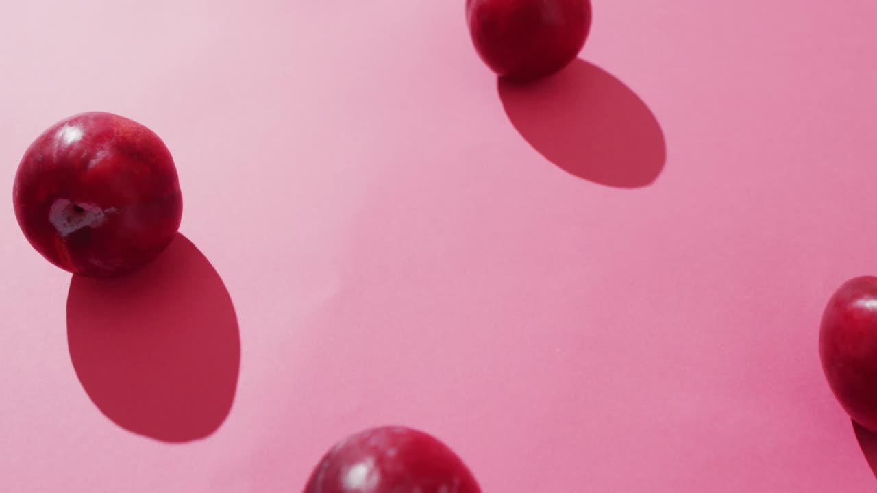Video of fresh plums lying on pink surface