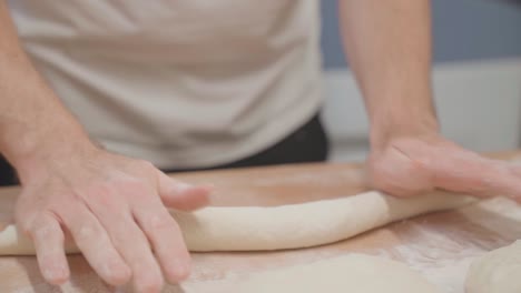 baker rolling baguette dough, close up