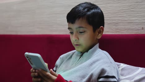 young-kid-watching-mobile-and-playing-online-game-at-home-at-night-from-different-perspective