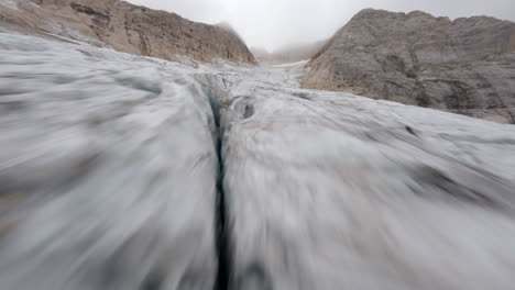 Racing-drone-flying-over-at-low-altitude-over-Marmolada-Glacier,-Trentino-in-Italy