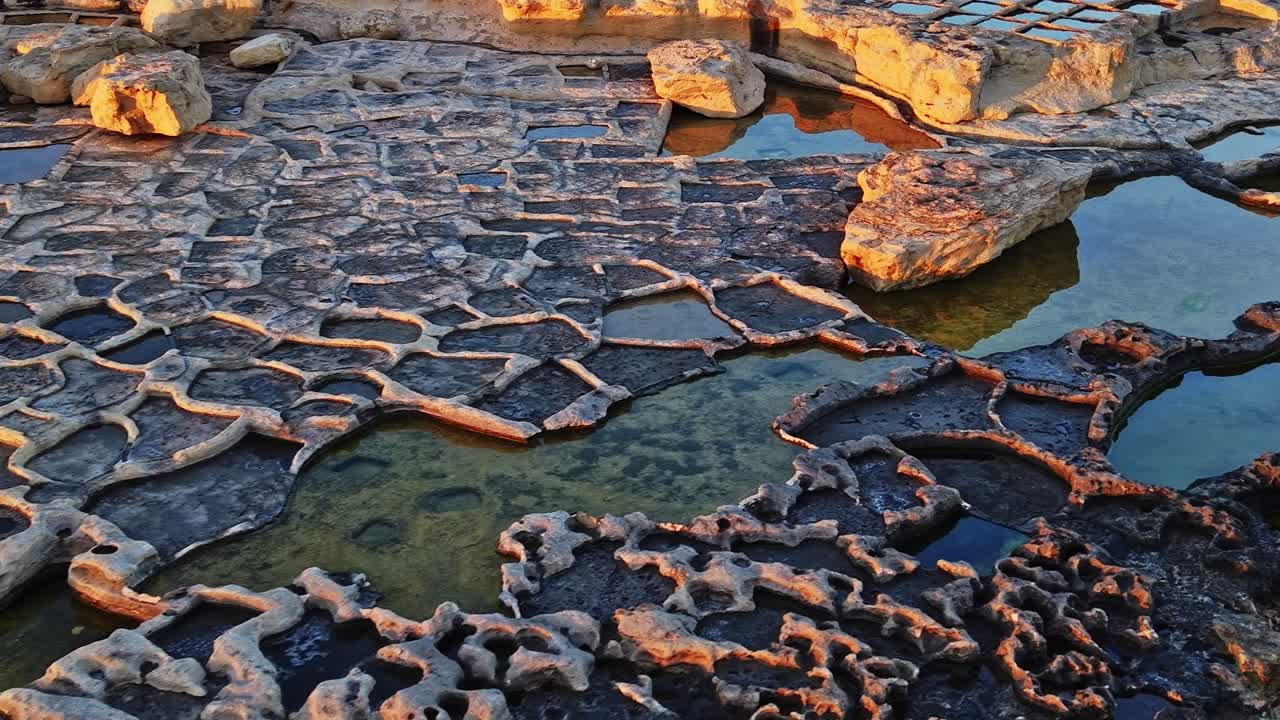 Udforsk de naturlige klippeformationer og vandhuller på Malta ved solnedgang