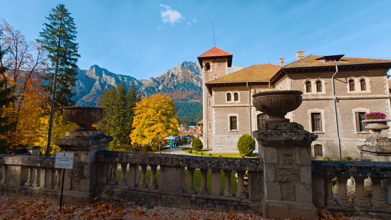 Amazing view of the old-fashioned palace in the rays of bright autumn sun. Stunning scenery of a castle at backdrop of colorful trees and bare mountains.