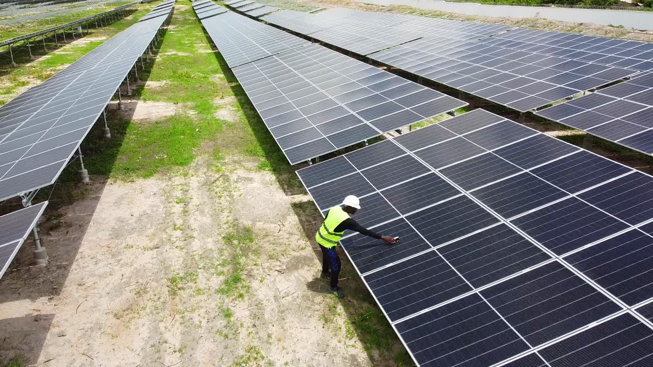 Aerial view of engineer taking new solar panel tilt angle measurements at NAWEC TBEA solar power plant in Jambur - Gambia