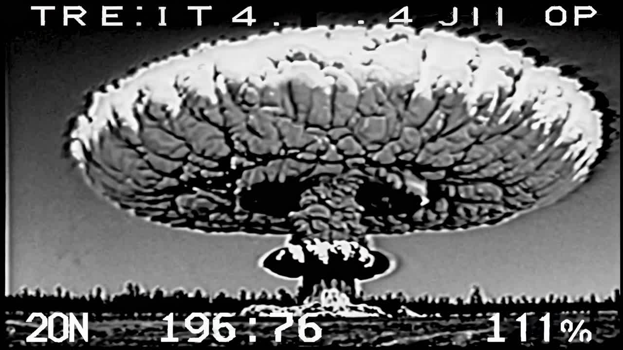 Filmato in bianco e nero di un'esplosione nucleare, ripreso da un'angolazione bassa, che mostra un fungo atomico.