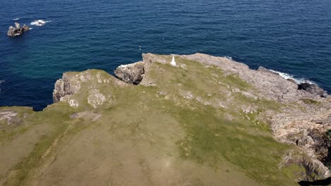 tiro de dron inclinado de un faro rodeado de acantilados y aves marinas que anidan