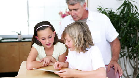 children using a tablet computer in front of their father