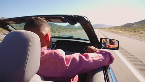 Two-Men-In-Convertible-Car-Driving-Along-Road-Shot-On-R3D