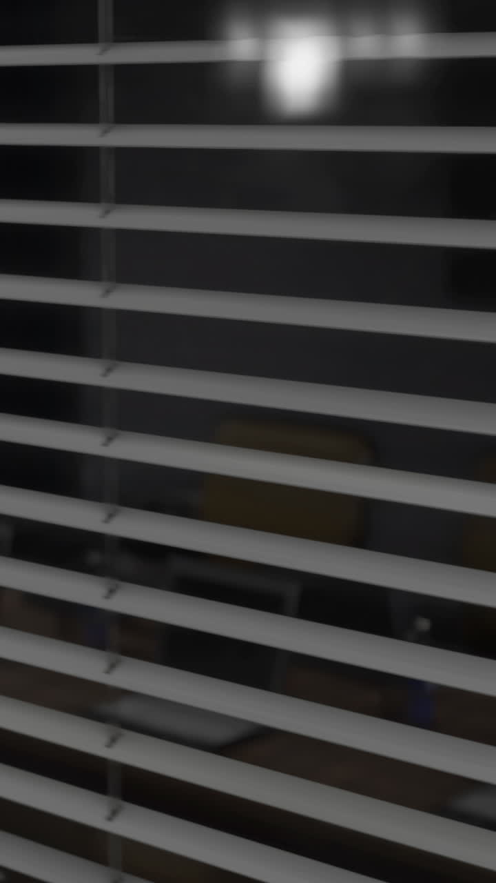 Horizontal blinds filter light in a dark room creating a serene atmosphere