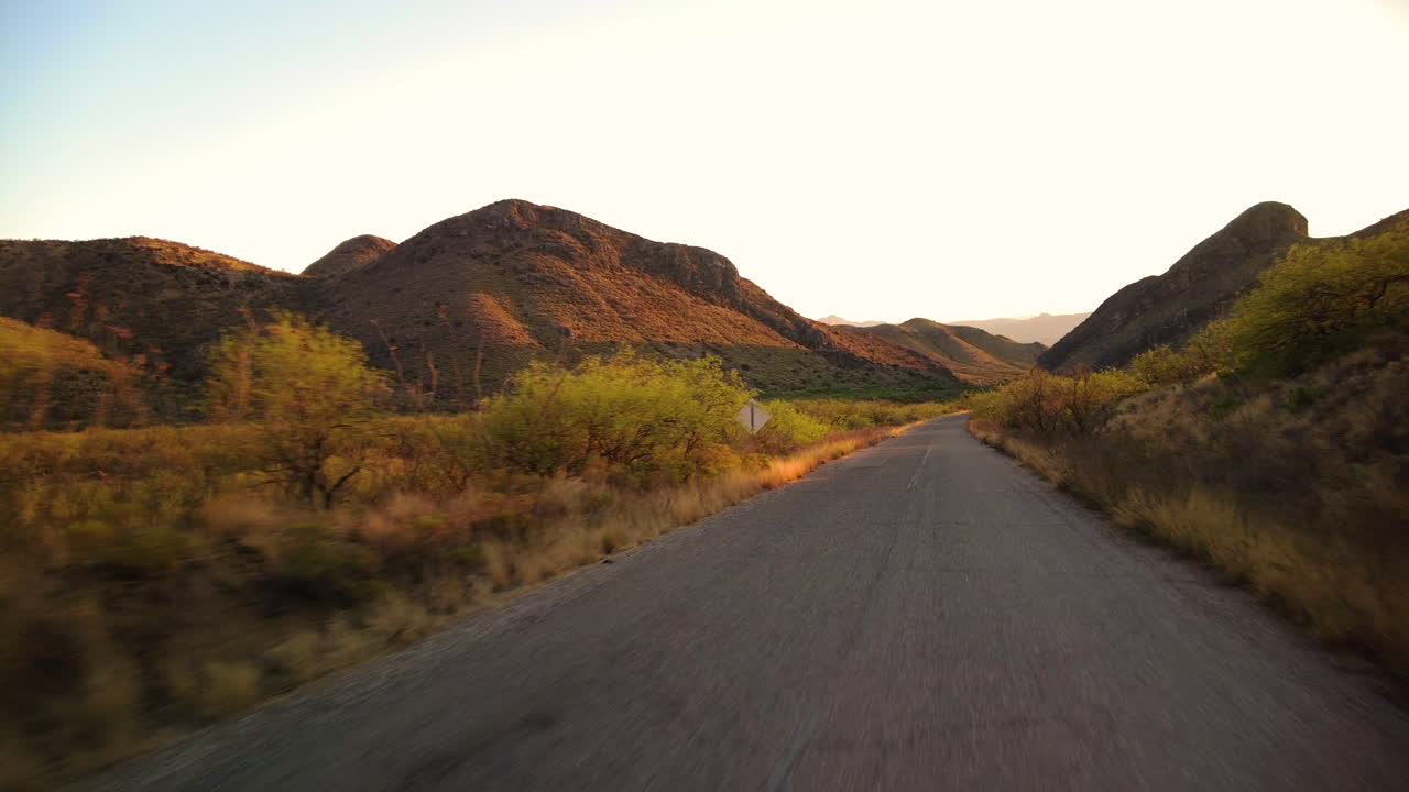 conduciendo por una carretera rural a través de colinas en arizona al amanecer