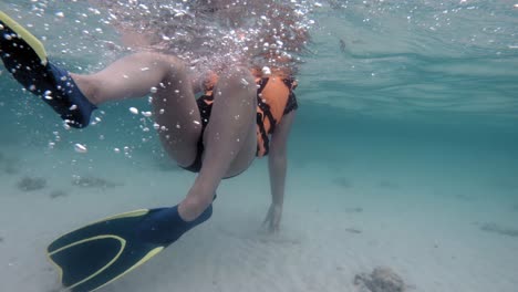 woman snorkeling in crystal clear water and white sand beach - medium shot