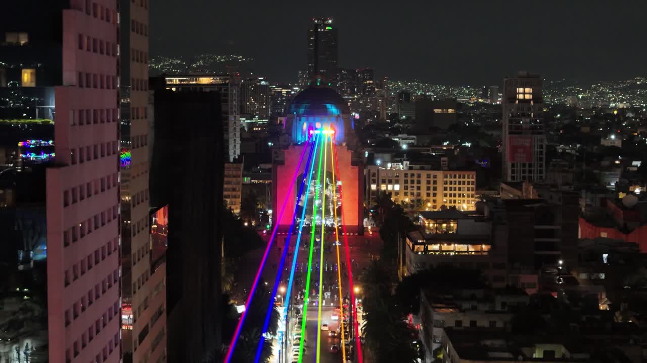 backwards drone shot of pride colors laser light in mexico city revolution monument