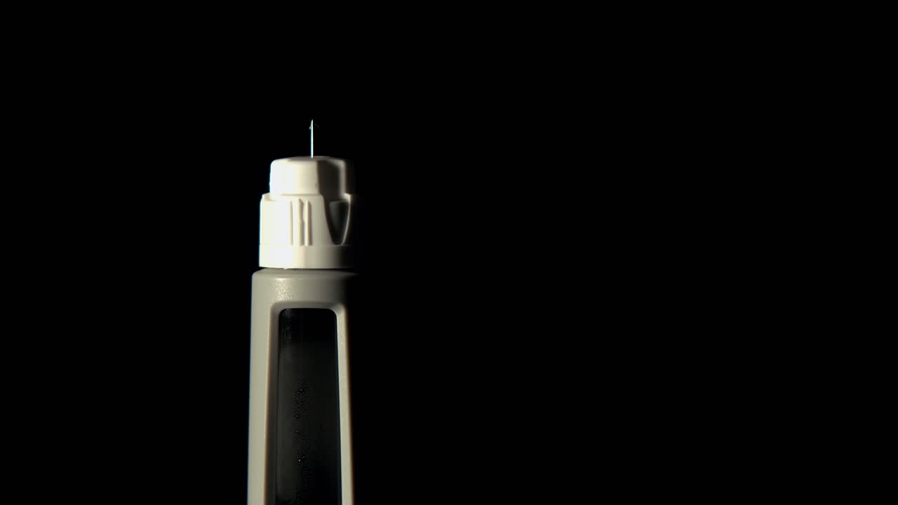 Closeup: Light sweeps across isolated injection needle with droplet
