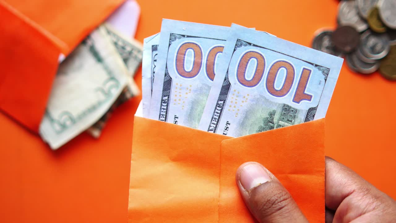 우리와 함께 오렌지색 봉투를 들고있는 손 100 달러 지폐