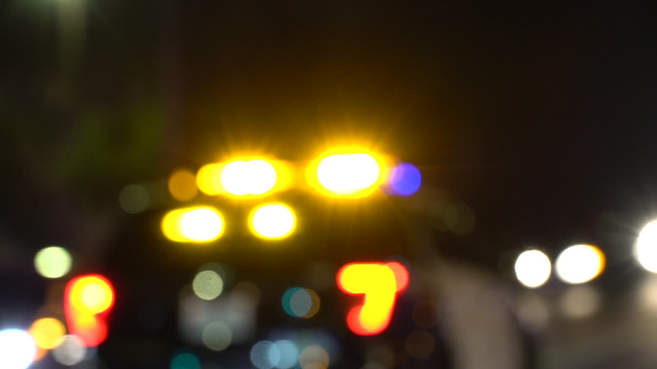 un coche de policía pasa por la noche con luces bokeh brillantes