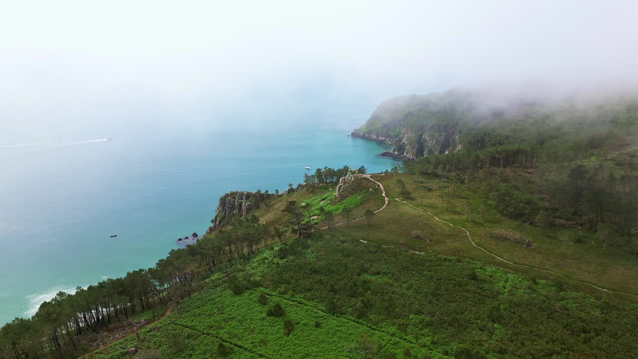 Drone aerial perspective of coastal Ile Vierge beach in Crozon Peninsula, Brittany , France, with turquoise water and rugged coastline shrouded in mist creating a serene atmosphere