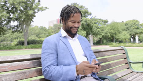 Corporate-black-man,-park-and-phone-for-texting