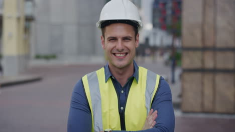 retrato joven ingeniero exitoso hombre sonriendo brazos cruzados disfrutando de la carrera en la industria de la construcción usando casco de seguridad fondo de la ciudad cámara lenta