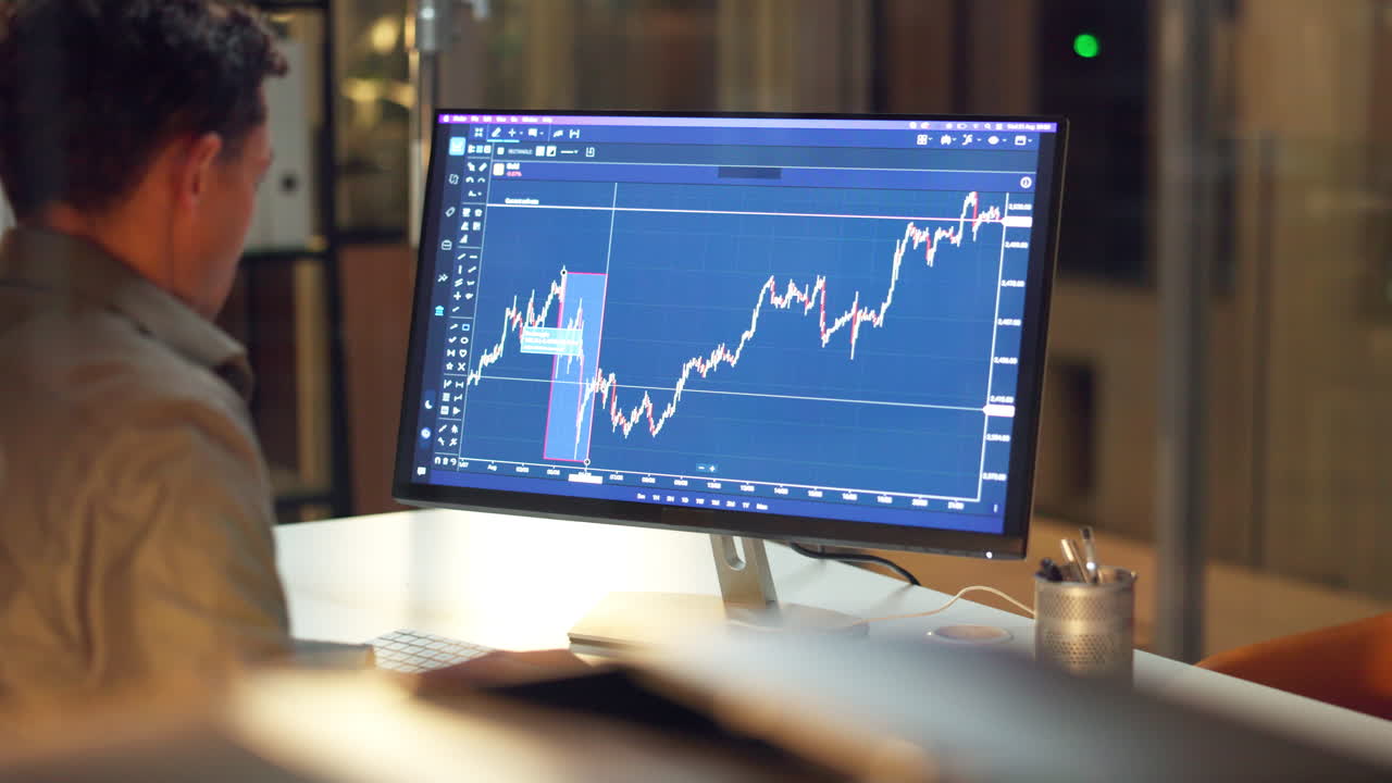 Person analyzing stock market data on computer at night