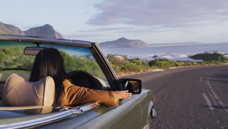 African-american-woman-driving-along-country-road-in-convertible-car