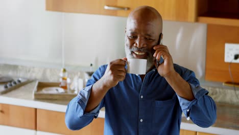 Älterer-Mann-Trinkt-Schwarzen-Kaffee,-Während-Er-In-Der-Küche-Mit-Dem-Mobiltelefon-Spricht-4k