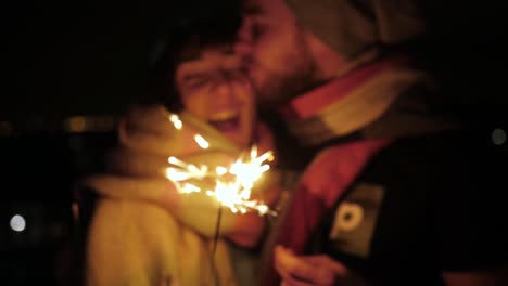 happy young caucasian couple in love with sparklers hugging smiling