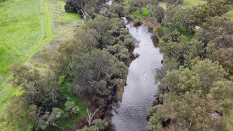 aerial tilt down view over single white kayak paddling down river