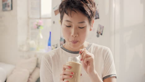 asian girl indulging eating peanut butter from jar using spoon