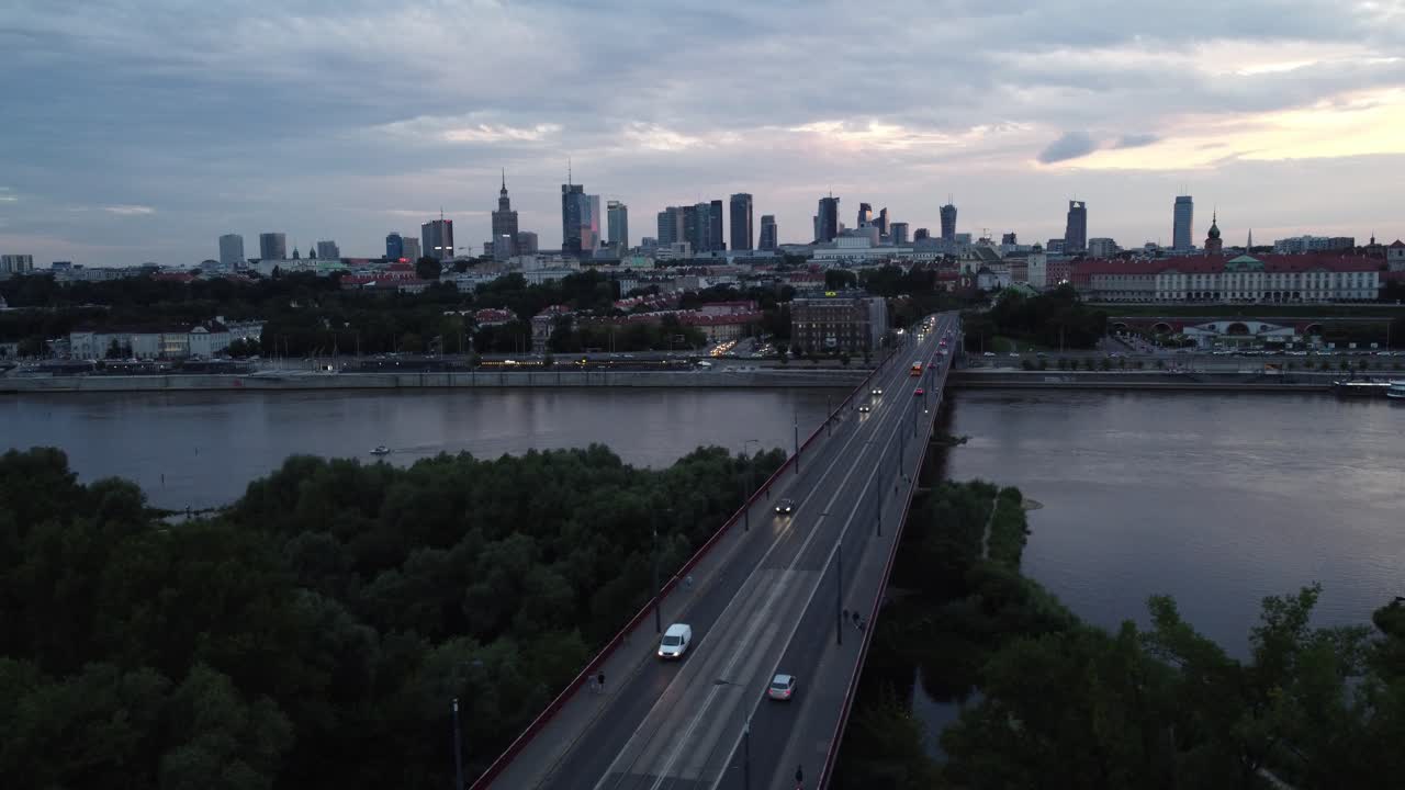 Rekaman drone sinematik cakrawala Warsawa dengan Sungai Vistula dan jembatan yang penuh lalu lintas di malam hari.